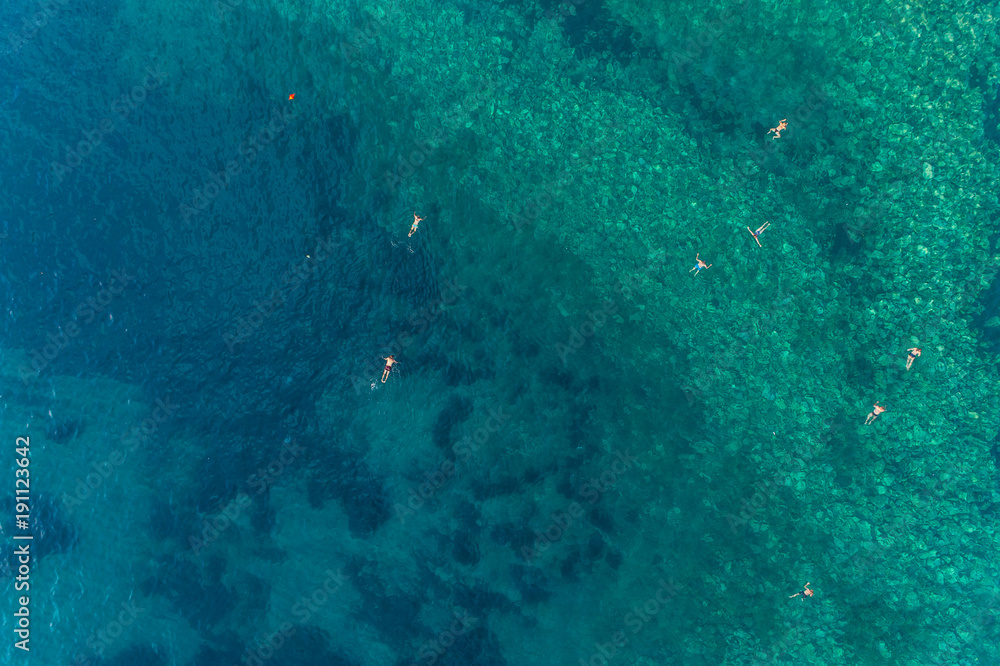 Fototapeta premium Aerial view of the turquoise sea surface in which people bathe 