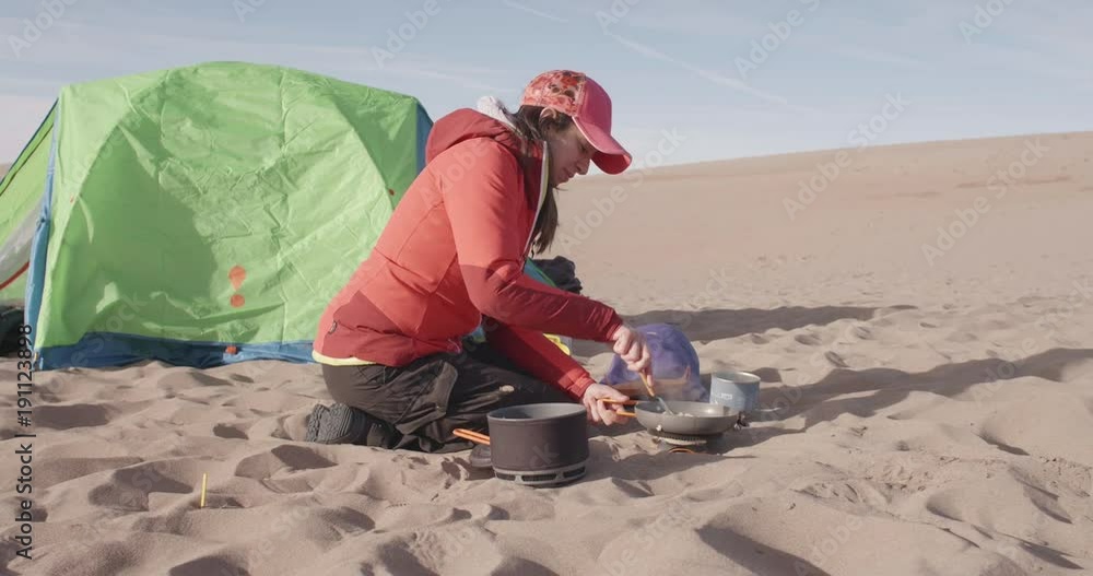 Hispanic Woman Cracking an Eggs in a Frying Pan on a Backpacking Stove