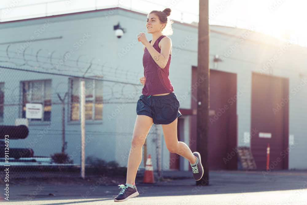 Pretty woman athlete running at sunset at industrial city area Pretty woman athlete running at sunset at industrial city area