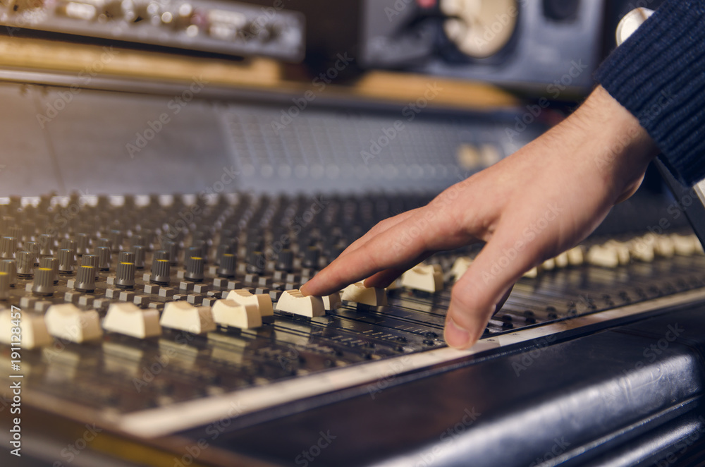 Man adjusting analog mixing desk in studio Man adjusting analog mixing desk in studio