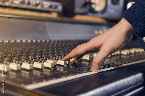  Man adjusting analog mixing desk in studio 