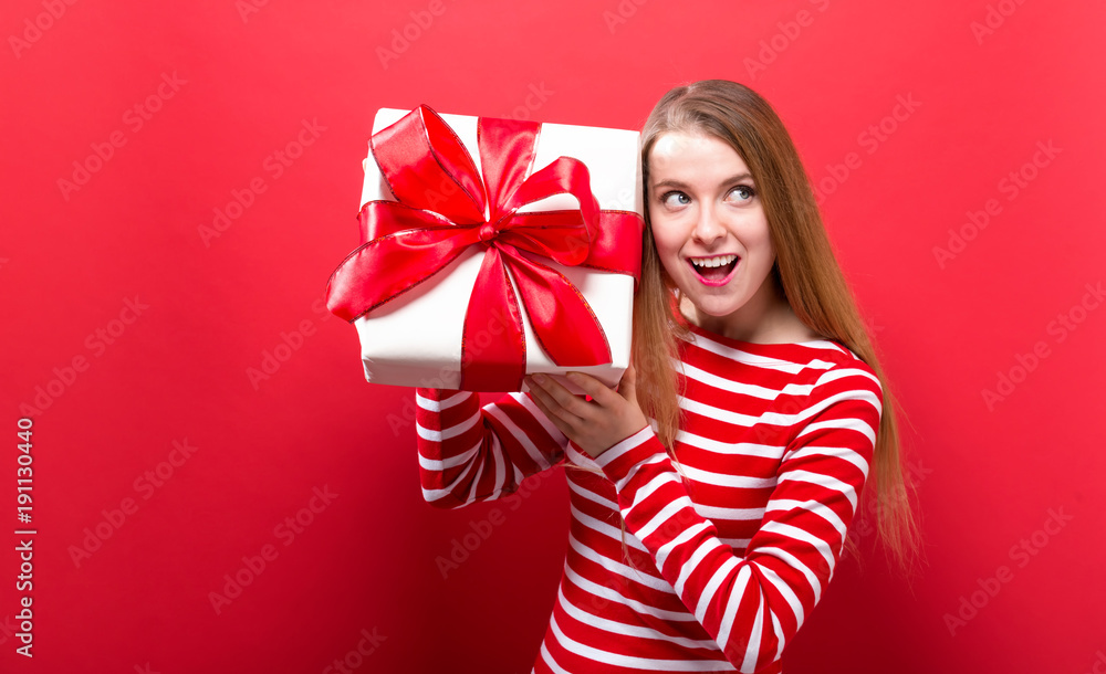 Happy young woman holding a gift box on a red background Happy young woman holding a gift box on a red background