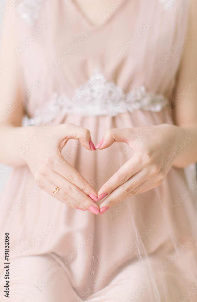 Pregnant girl sits on a decorated chair and formed heart whith hands Pregnant girl sits on a decorated chair and formed heart whith hands
