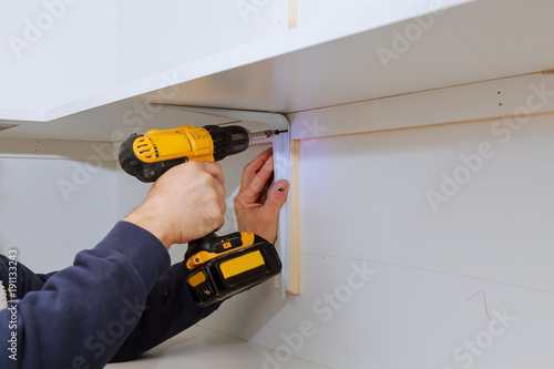 фотографія Man installing wooden shelves on brackets wall installing a shelf