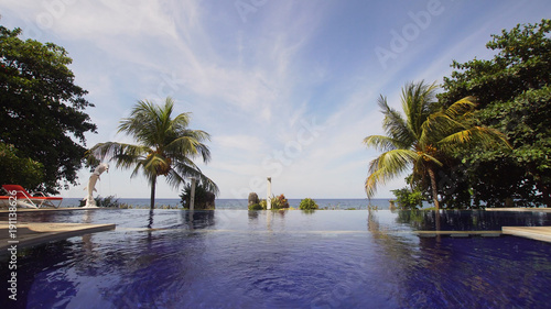 Luxury hotel resort near at sea with pool among the palm trees. Luxurious open air swimming pool at resort. Swimming pool with turquoise water in hotel. Travel concept.