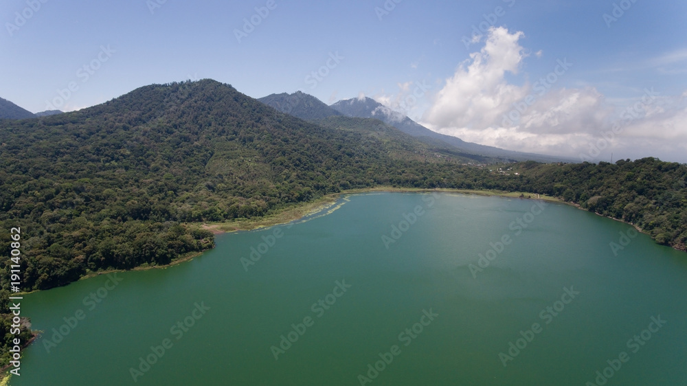Obraz premium Aerial view of Lake Tamblingan, a caldera lake at Bali. Beautiful lake with turquoise water in the mountains of the island of Bali. Landscape, lake among mountains, sky, clouds.