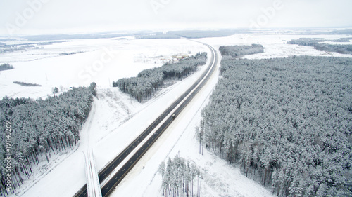 Winter forest and the road. View from above. The photo was taken with a drone. Pine and fir forest in the snow
