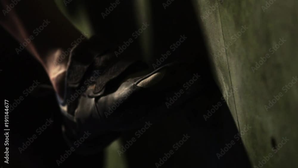 Close-up of a climber climbs on a stone wall indoors. The Sculpture. The leg slowly rises from the excavation and the athlete moves up. Close-up of a climber climbs on a stone wall indoors. The Sculpture. The leg slowly rises from the excavation and the athlete moves up.