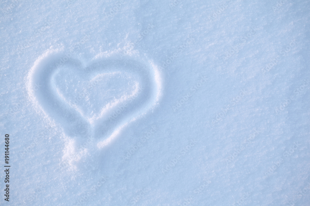 The heart is painted in the snow. Background of a blue color for a holiday card for Valentine's Day.