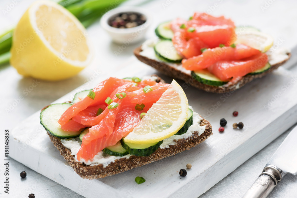 Rye bread with smoked salmon, cream cheese and cucumber on white cutting board. Healthy appetizer Rye bread with smoked salmon, cream cheese and cucumber on white cutting board. Healthy appetizer