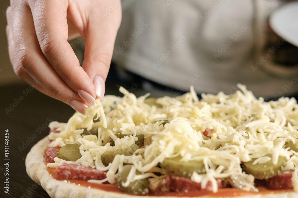 chef sprinkles cheese pizza,  a lot of cheese on a pizza,  cooking process, woman holding cheese in hands,  close-up,  homemade pizza,
