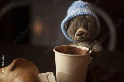 Teddy bear a soft toy with a cup of hot chocolate in the interior of a cafe photo