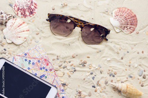 Enjoying vacation mood, a telephone and sunglasses on white sand background. Space for a text or product display, top view. photo