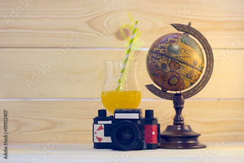 Enjoying vacation planning mood, globe, drink and vintage camera on white sand background photo