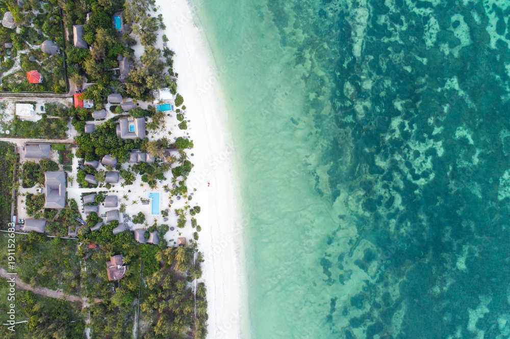 Beautiful turquoise ocean meets African island with houses and palms on Zanzibar, Aerial photo, top view