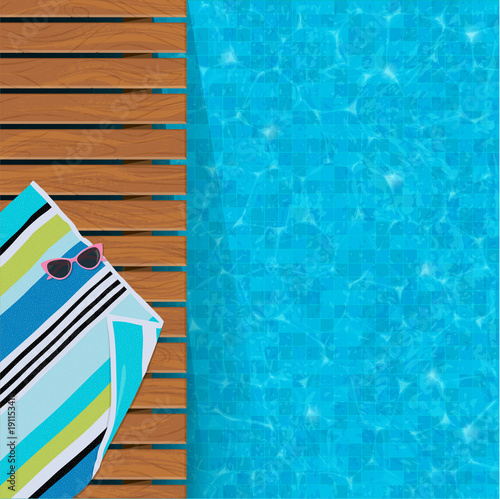 Relaxing swimming pool edge with teak wood deck, Sunglasses on beach towel. Plenty of copy space.