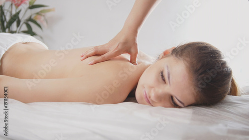 Young female relaxing in spa salon - oil sesame massage