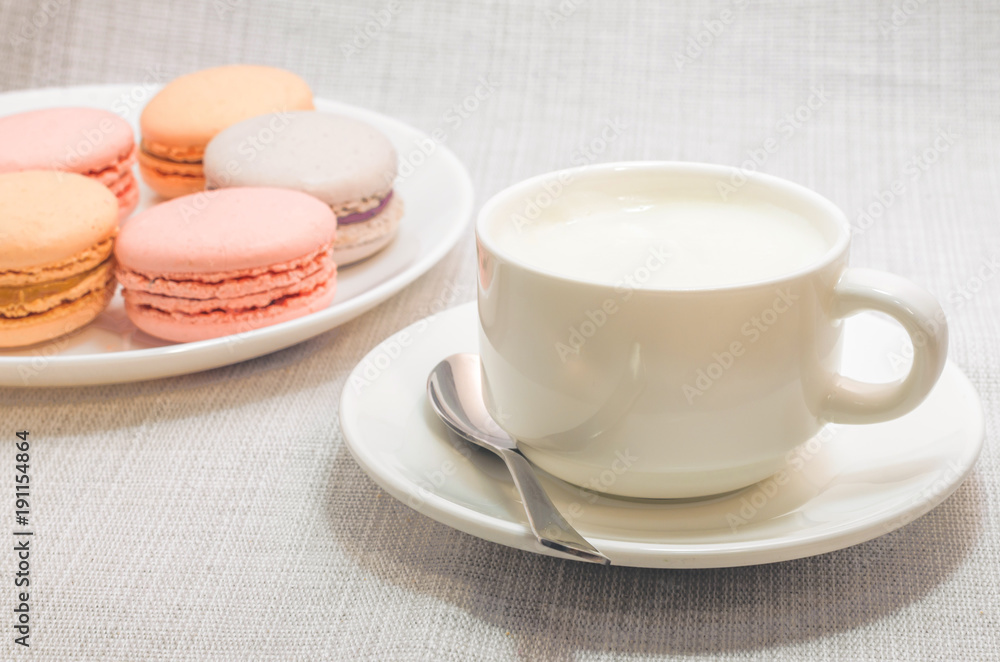 Cake macaroon on the plate and a frothy coffee, close up Cake macaroon on the plate and a frothy coffee, close up