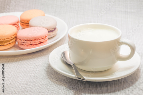 Cake macaroon on the plate and a frothy coffee  close up