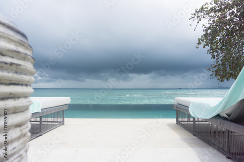 Poolside seating and outlook to tropical dark cloudy sky.