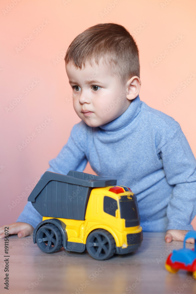 A cute little boy playing with model car collection. Toy mess in child room. Educational games for kids. A cute little boy playing with model car collection. Toy mess in child room. Educational games for kids.