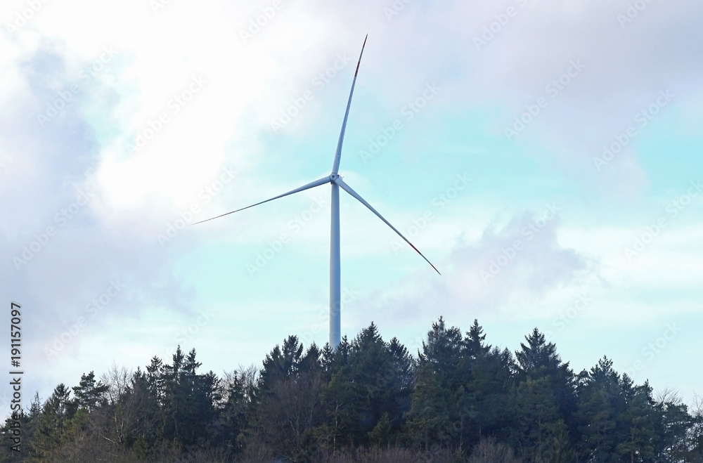 Fototapeta premium wind turbine in a forest, cloud-sky