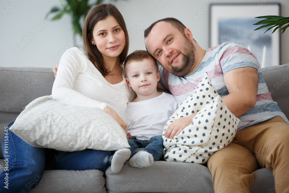 Image of hugging family with son on gray sofa Image of hugging family with son on gray sofa