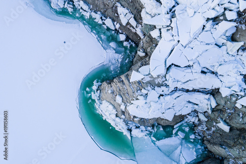 Thaw lake, blocks of ice and turquoise water. View from above with drone