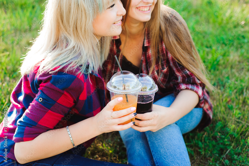 Friends drinking juice on green grass in the park Friends drinking juice on green grass in the park