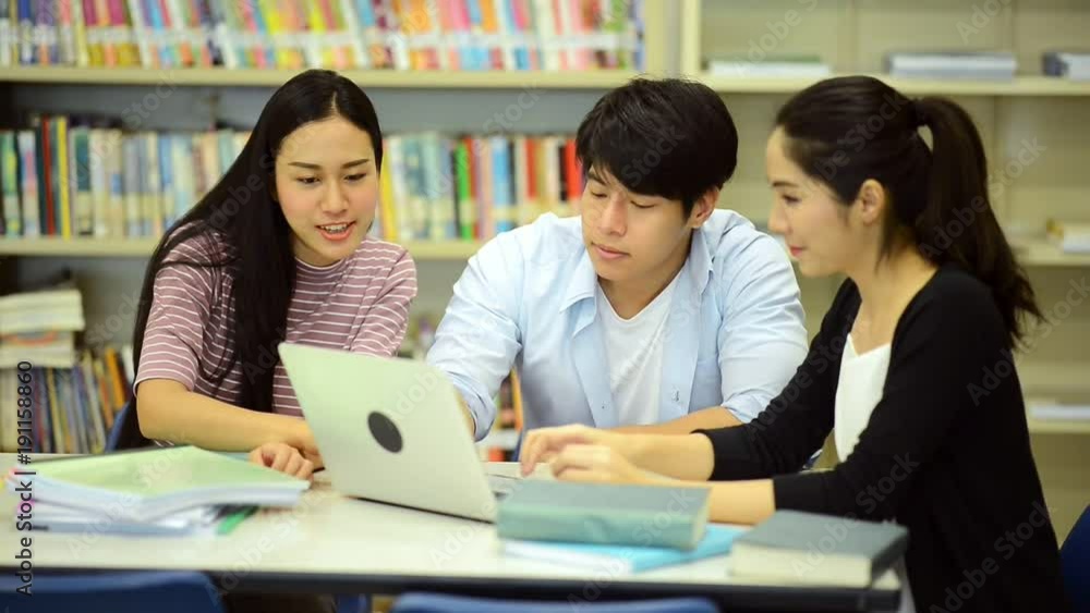 Young students study hard in library. Happy Asian female and male university students doing study research in library with books on desk, notebook. For back to school education diversity concept. Young students study hard in library. Happy Asian female and male university students doing study research in library with books on desk, notebook. For back to school education diversity concept.