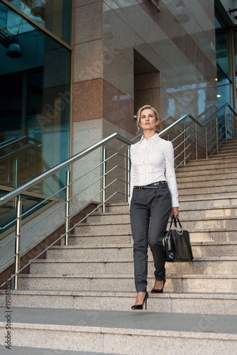 Business woman in pants with briefcase walking on stairs