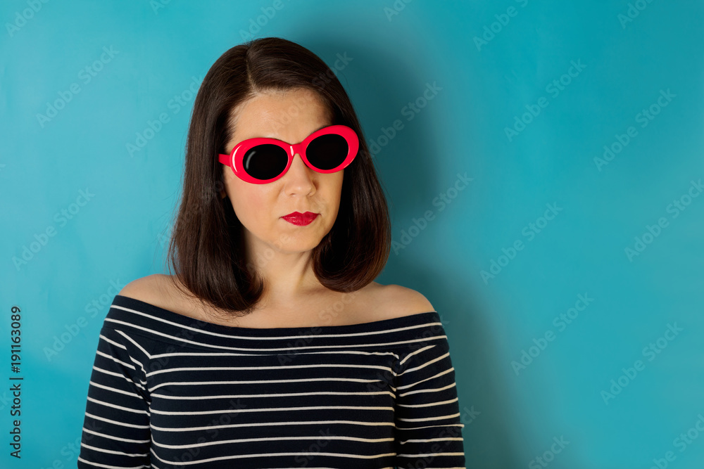 Woman in blue striped top and red sunglasses on a blue background. Woman in blue striped top and red sunglasses on a blue background.