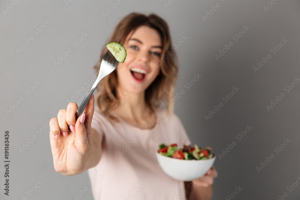 Playful woman in t-shirt holding plate with fresh vegetables Playful woman in t-shirt holding plate with fresh vegetables