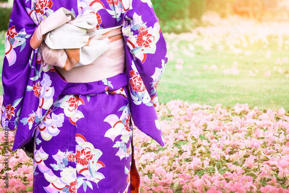 Young woman wearing kimono traditional Japan walking in a flowers garden in winter.