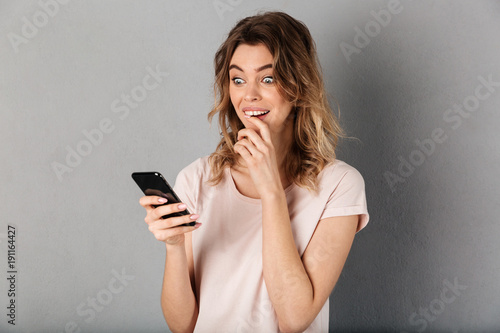 Image of Surprised woman in t-shirt writing message on smartphone