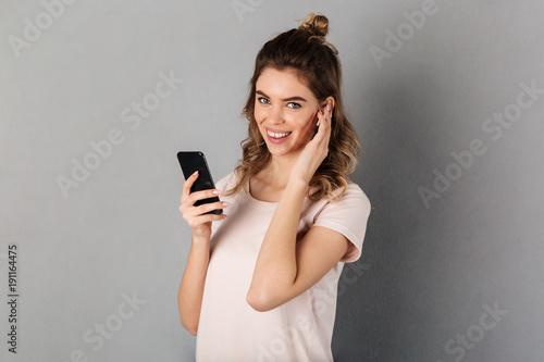 Joyful woman in t-shirt listening music from smartphone