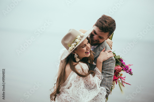 Foto beautiful happy bride and groom in boho style laughing at lake