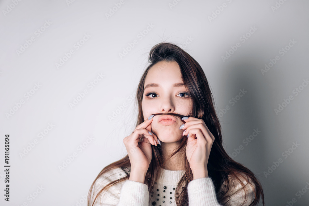 Cute lovely young woman making moustache with her hair Cute lovely young woman making moustache with her hair
