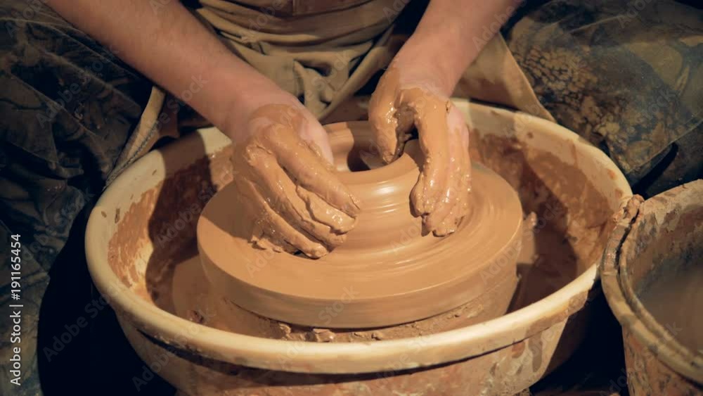 Potters hands make a wide low bowl on a wheel. Potters hands make a wide low bowl on a wheel.