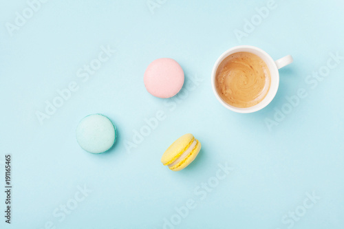 Composition with coffee and colorful macaron on pastel blue background top view. Cozy morning breakfast. Fashion flat lay style. Sweet macaroons.