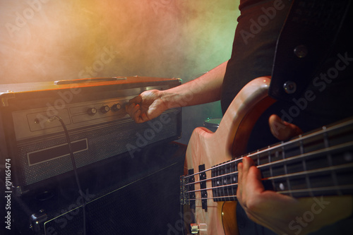 The bass guitarist connects the bass guitar to the amplifier on the stage.