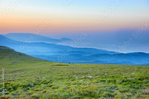 Sunset in the mountains with rocks and green grass