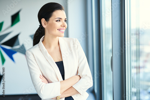 Successful businesswoman at corporate office looking through the window with confidence