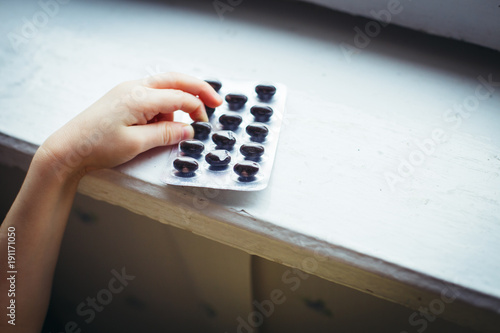 Baby in danger playing with a package of pills at home without parents. Safety concept photo