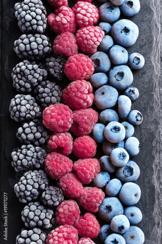 Frozen berries on black slate. Blueberry, raspberry, blackberry. Top view. High resolution product.