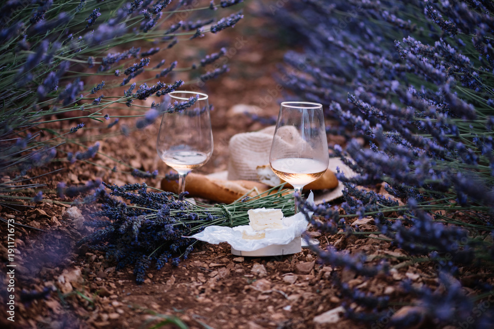 Obraz premium Wiekowy ser camembert, świeżo upieczone bagietki, dwie szklanki wina różowego i bukiet świeżo zebranego pikniku lawendowego w lawendowym polu, lato Prowansja, południowa Francja