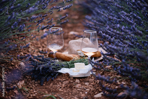 Fototapeta Naklejka Na Ścianę i Meble -  Aged camembert cheese, freshly baked baguettes, two glasses of rose wine and a bouquet of freshly picked lavender-picnic in the lavender field, summer Provence, south France
