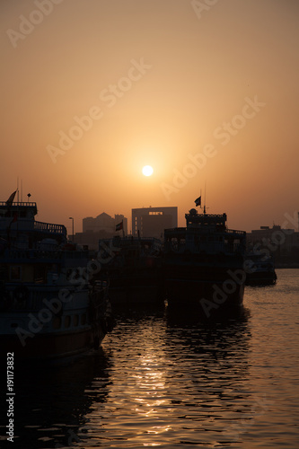 Old traditional ships, Dhows, in the harbour in Dubai creek at sunset
