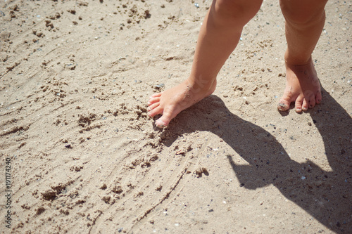 A child's feet standing on the sea sand