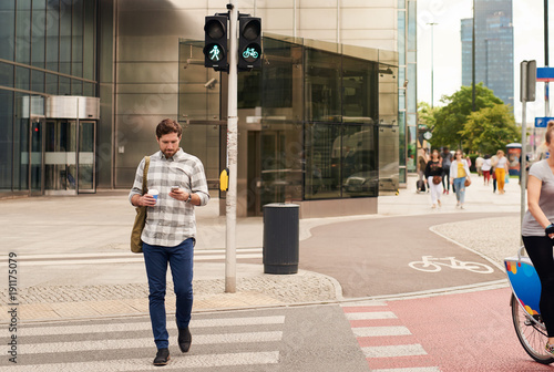 Obraz na płótnie Young man walking through the city using a cellphone